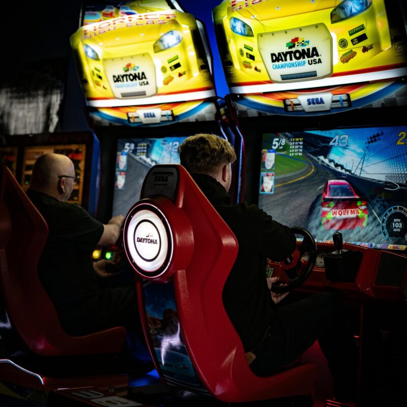 People enjoying an intense arcade racing game session, capturing the thrill and fun of Daytona Championship USA.